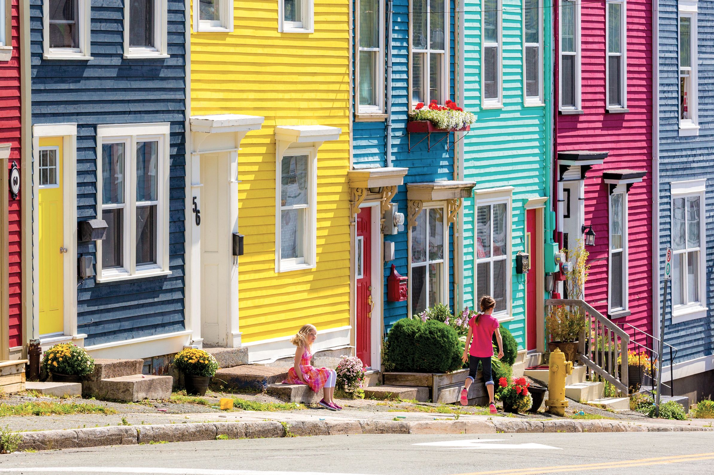 Kinder spielen vor einer bunten Hausfassade in St. John's